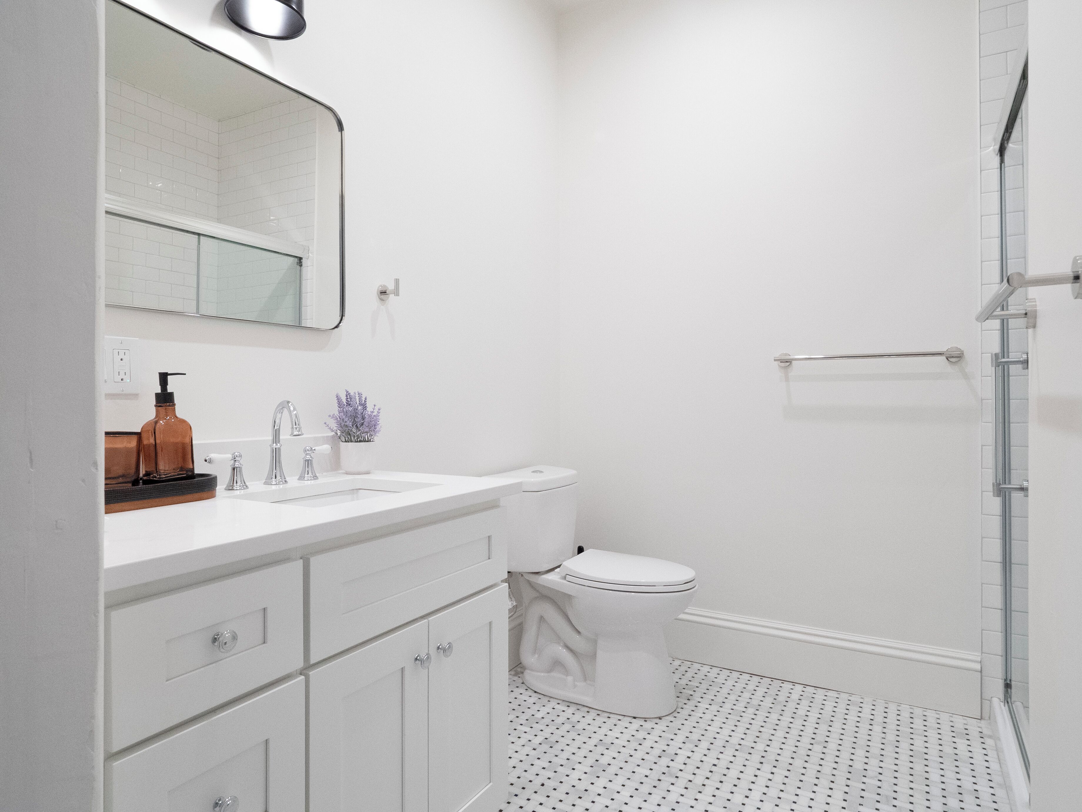 A modern bathroom with a white sink, a toilet, and a glass shower enclosure.