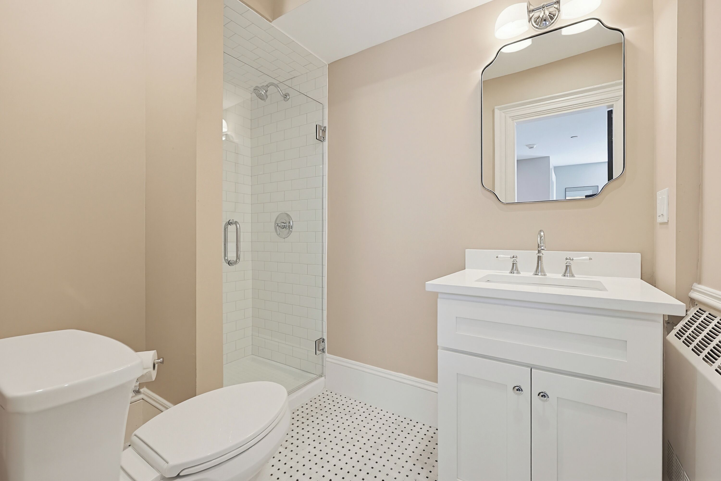 Een badkamer met toilet, douche, wastafel en spiegel.