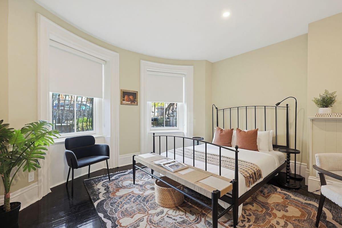 Un dormitorio con una cama, una silla, una planta en maceta y una ventana.