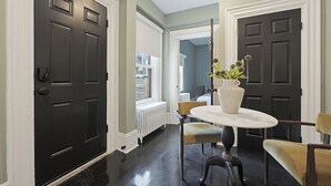 Un couloir avec des portes en bois foncé, un radiateur blanc et une table avec des chaises.