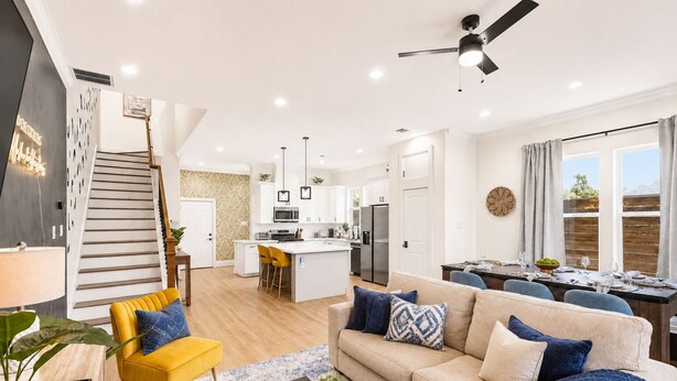 A modern living room with a sofa, yellow armchair, and a dining area with a table set for four.