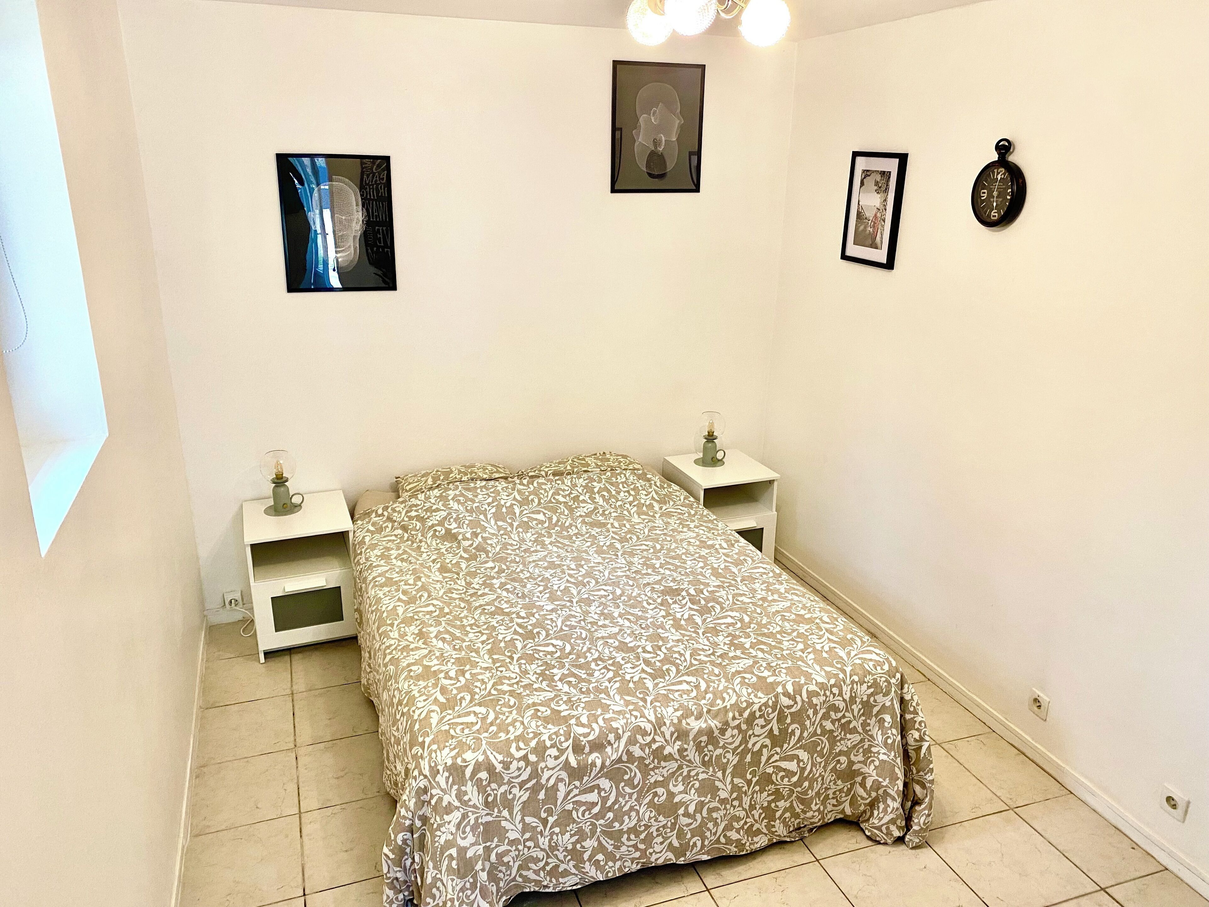 Una camera da letto con un letto, due comodini, un tavolino e due quadri appesi al muro.