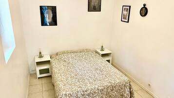 Una camera da letto con un letto, due comodini, un tavolino e due quadri appesi al muro.