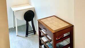A small, clean room with a white desk, a chair, a window with blinds, a wall-mounted shelf, and a framed picture. - Charmant Studio à Coutevroult (Coutevroult)