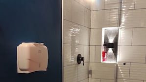 Baño con inodoro, secamanos y cabina de ducha.