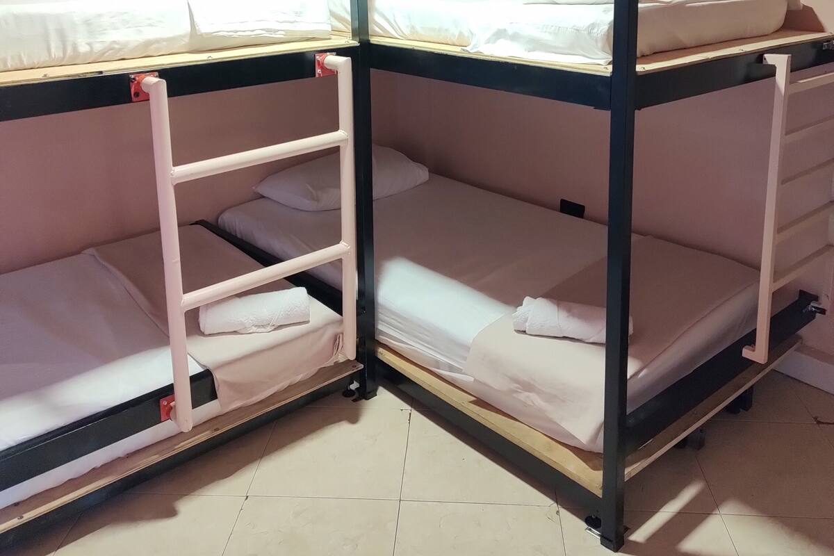 A bunk bed room with two beds, each with a pillow and a blanket.