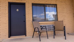 A building with a black door marked with the number 8, two chairs outside, and a window with a view of the sky. - The Golden Spurs (Panguitch)