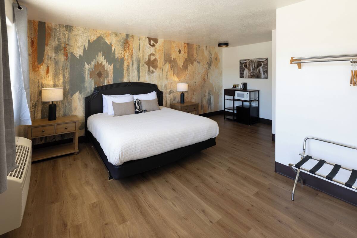A bedroom with a large bed, two bedside tables with lamps, a desk, and a chair.