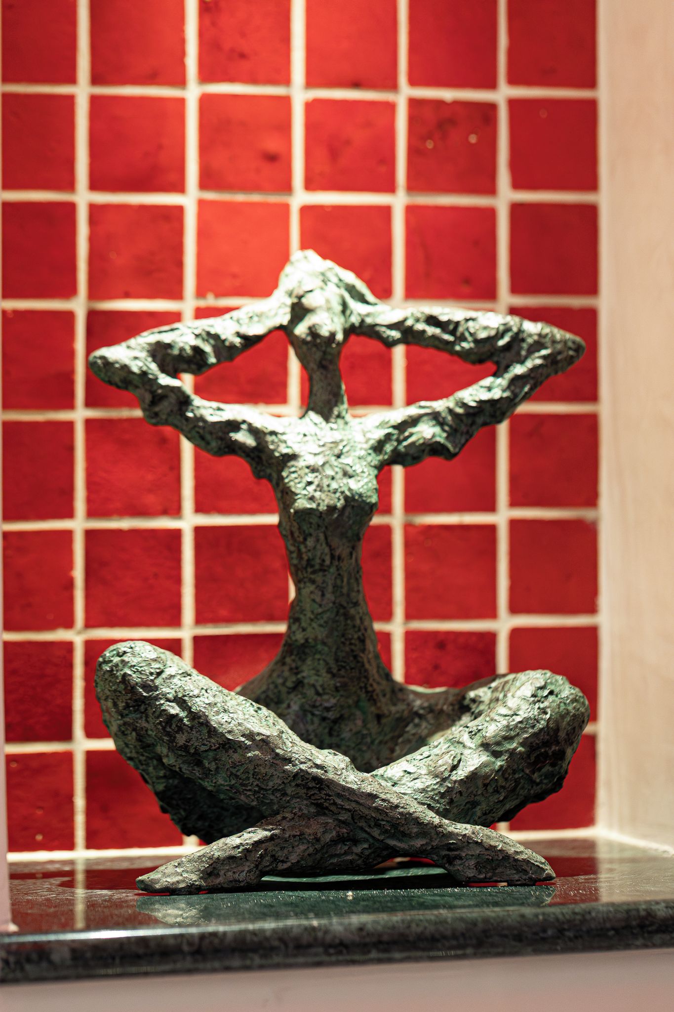 En skulptur med ett trädliknande fundament och en figur i en meditativ ställning.