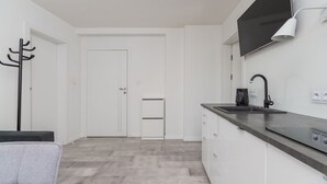 Eine moderne Küche mit weißen Schränken, einer schwarzen Arbeitsplatte und einem flachbildfernseher über der Spüle.