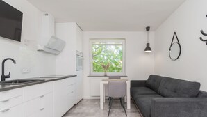 Eine moderne Küche mit weißen Schränken, einem schwarzen Wasserhahn und einem Fenster mit Blick auf Bäume.