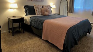Een netjes ingerichte slaapkamer met een bed, twee nachtkastjes, een spiegel en een schilderij aan de muur.