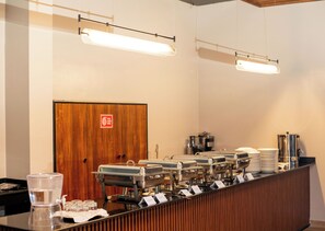 A buffet setup with multiple serving stations, a water dispenser, and a coffee machine.