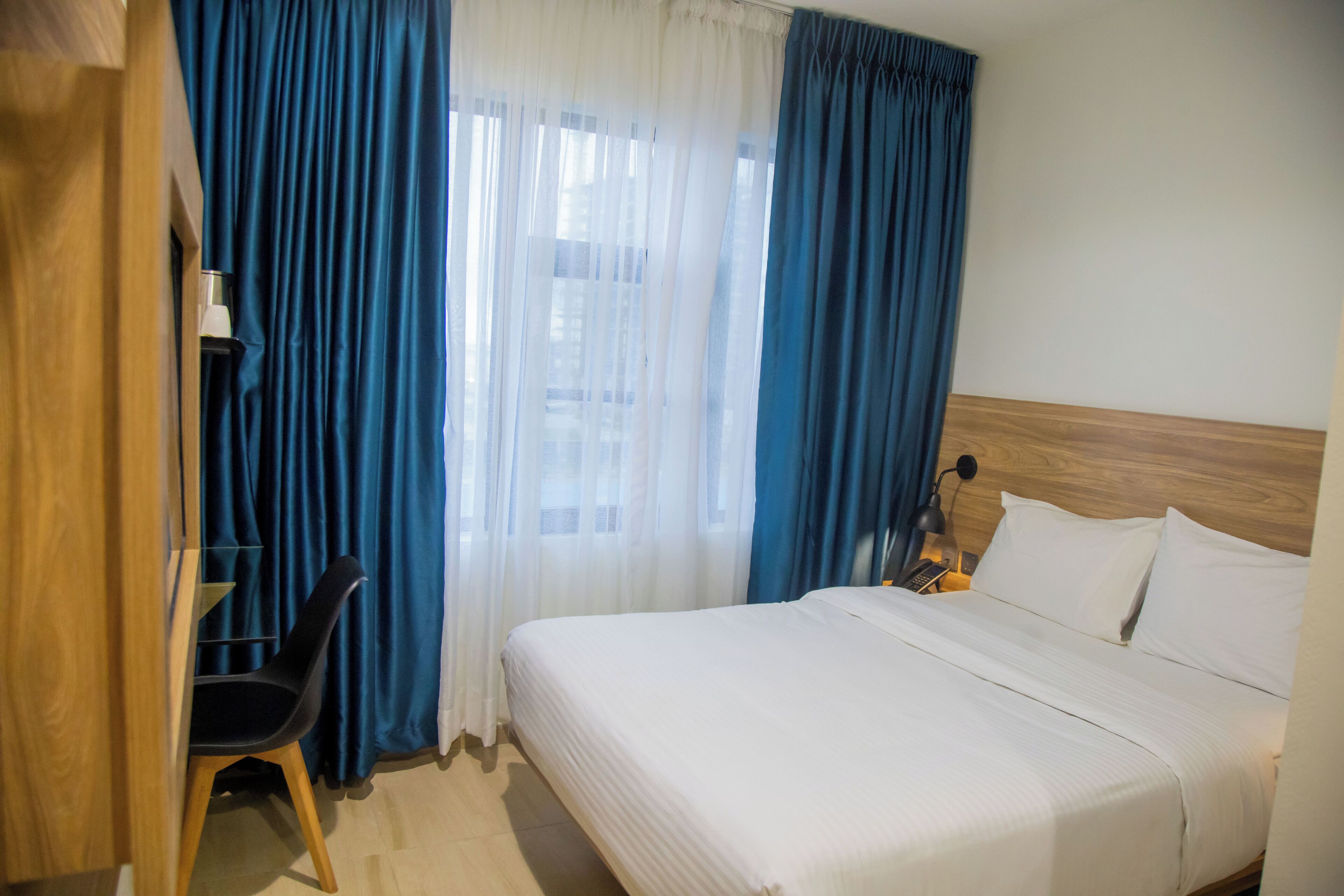 A hotel room with a bed, a desk, and a chair.
