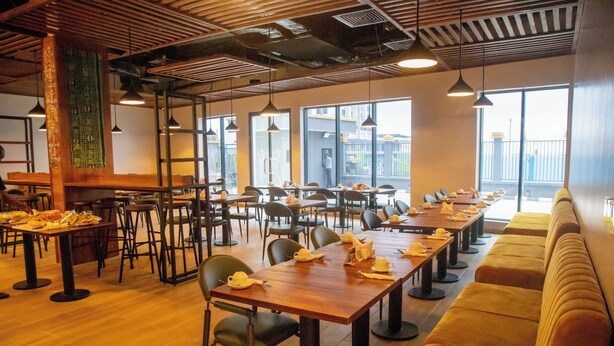A spacious restaurant with long wooden tables, black chairs, and a high ceiling with exposed beams. - Hotelinn Oniru  (Lagos)