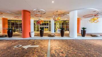 A modern lobby with a brick floor, large columns, and unique circular ceiling lights.