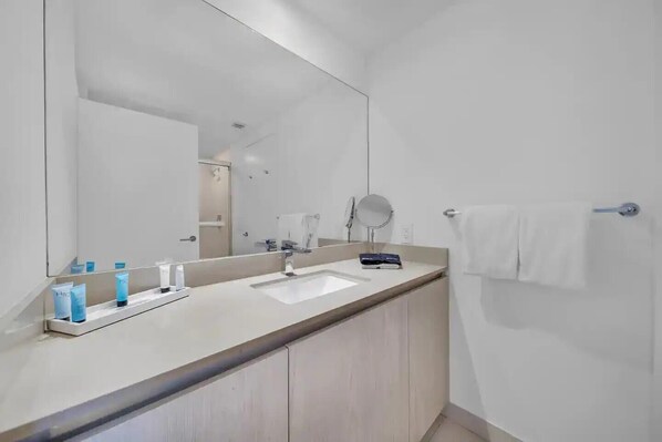 A modern bathroom with a large mirror, a sink, and a towel rack. - Lyfe Resort & Condo (Hollywood)