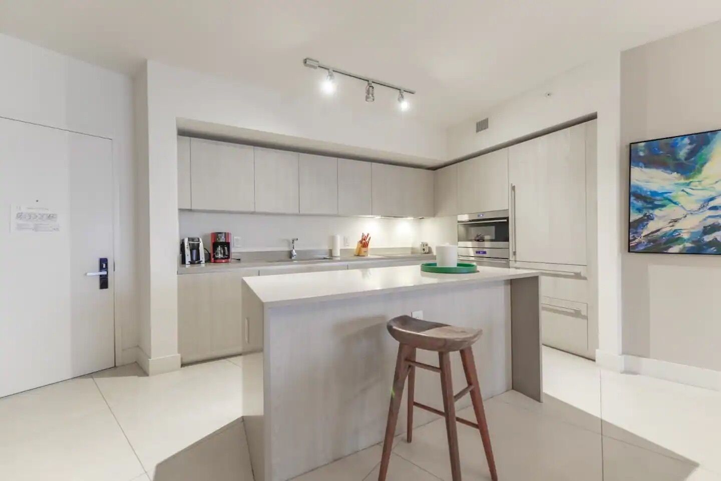 A modern kitchen with a central island, stainless steel appliances, and a bar stool.