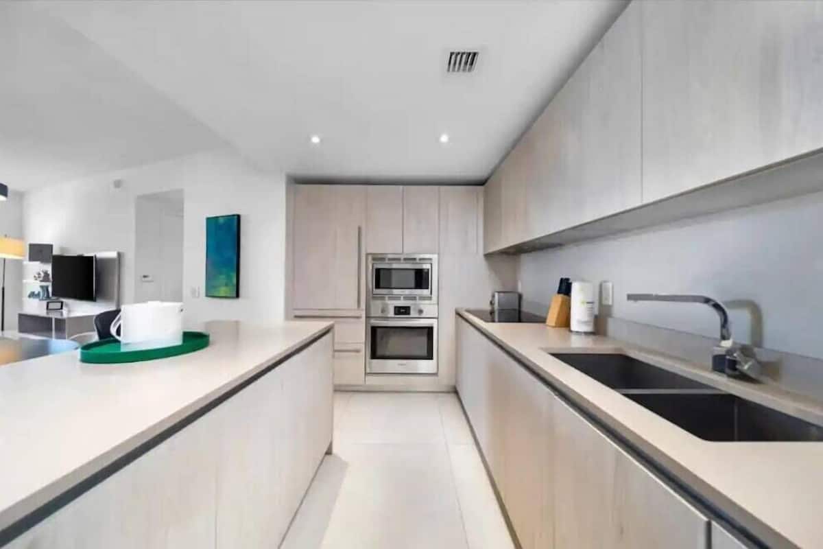 Een moderne keuken met een centraal eiland, een inbouwoven en roestvrijstalen apparatuur.