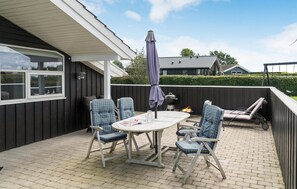 A patio with a table and chairs, a barbecue grill, and a covered area with an umbrella.