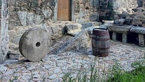 An outdoor courtyard with stone walls, a wooden door, and a barrel.