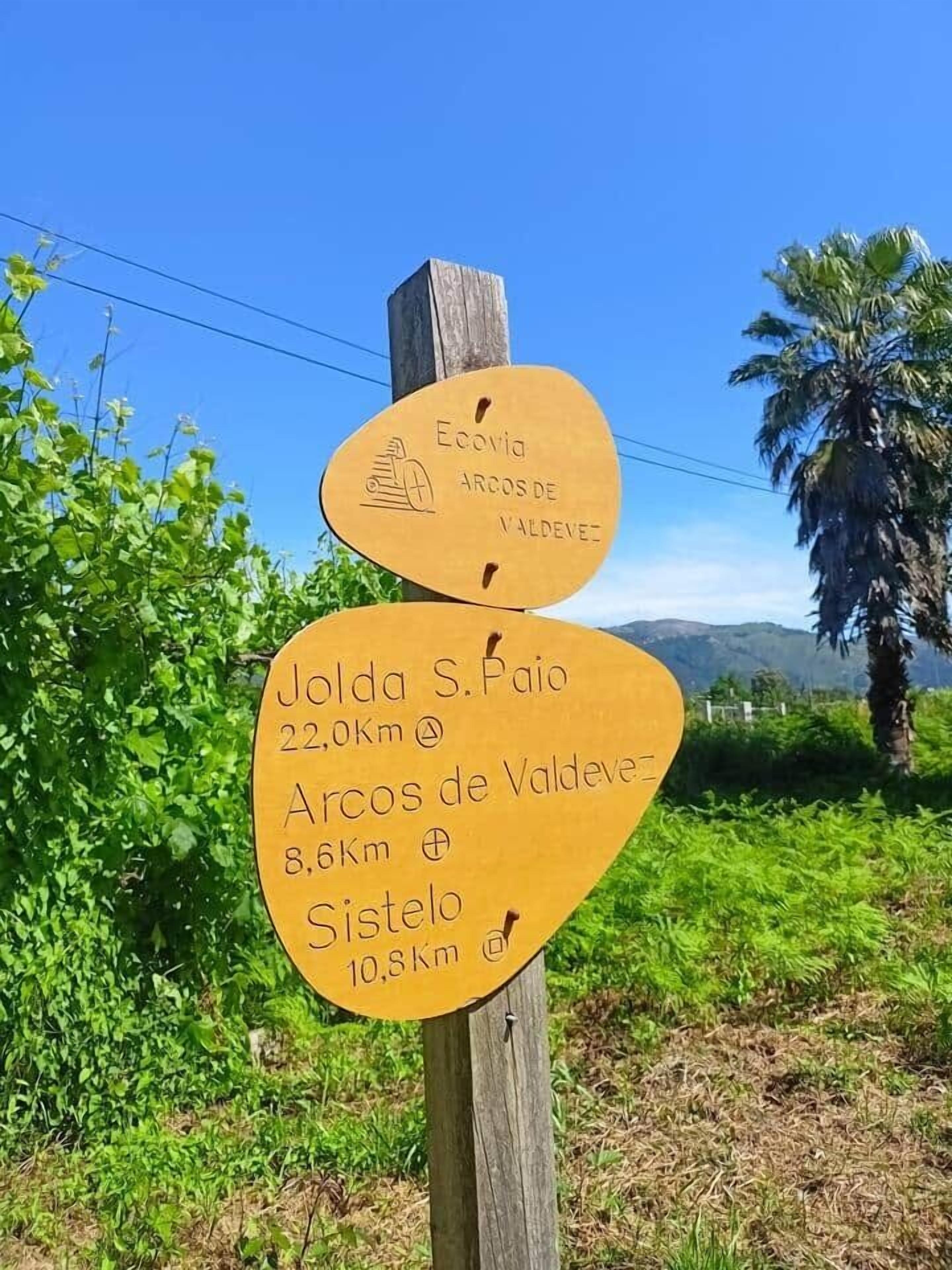 A wooden signpost with distance markers for Jolda S. Paio, Arcos de Valdevez, and Sistelo.