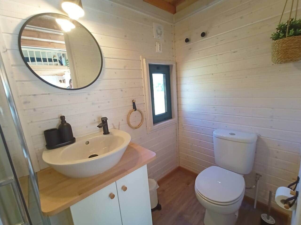 A compact bathroom with a sink, toilet, and a small window.