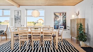 A dining area with a wooden table and chairs, a black and white striped rug, and a hanging pendant light. - 4 bedroom nice home in Harboøre (Harboøre)