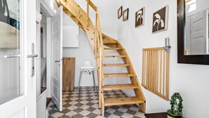 A wooden staircase in a room with a checkered floor, a radiator, and framed artwork on the wall. - 4 bedroom nice home in Harboøre (Harboøre)