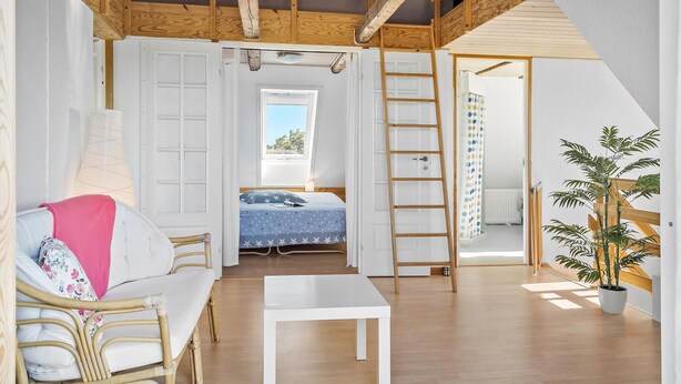 A compact bedroom with a bed, a white table, a wooden ladder, and a potted plant. - 4 bedroom nice home in Harboøre (Harboøre)