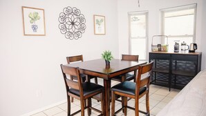 Een eethoek met een houten tafel en stoelen, een kleine potplant en een decoratief wandobject.