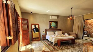 Une chambre spacieuse avec un grand lit, un coin salon doté d’un fauteuil confortable et une vue sur l’extérieur par une fenêtre.