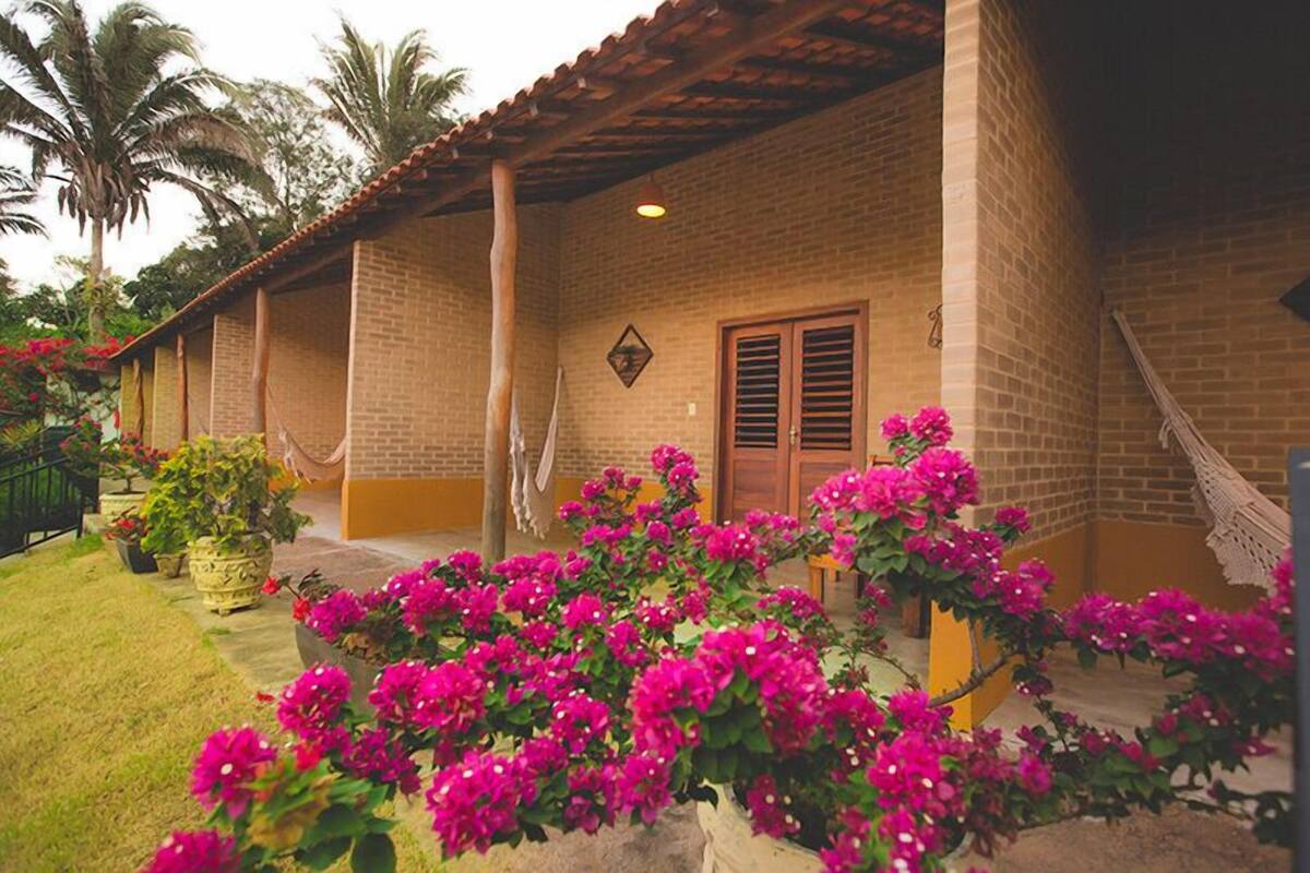 A brick building with a tiled roof, a wooden door, and a hammock.