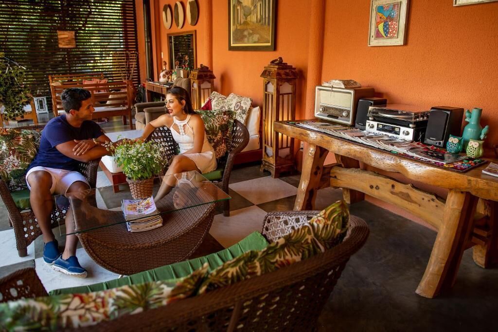 A cozy living room with wicker furniture, a glass coffee table, and a wooden table with electronic devices.