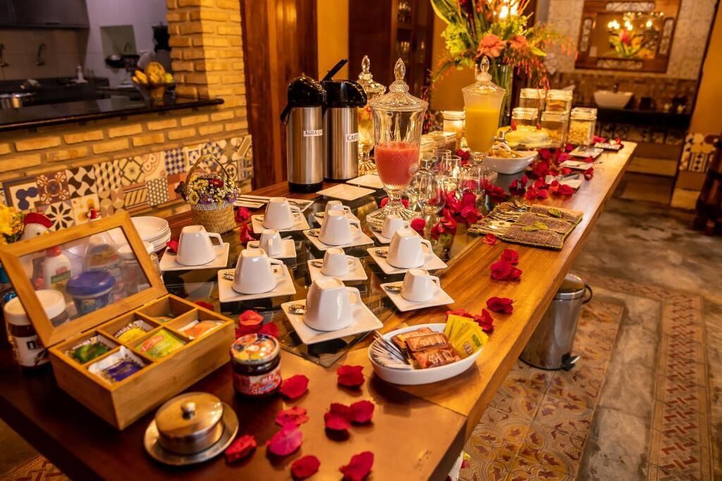 A breakfast buffet setup with various food items, a coffee station, and decorative elements like flowers and a framed picture.