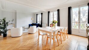 Un salon spacieux comprenant une table à manger et des chaises, un canapé bleu et une plante en pot.