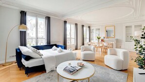 Une chambre d’hôtel moderne comprenant un lit, une table basse ronde, un canapé et un coin repas avec des chaises et une table.
