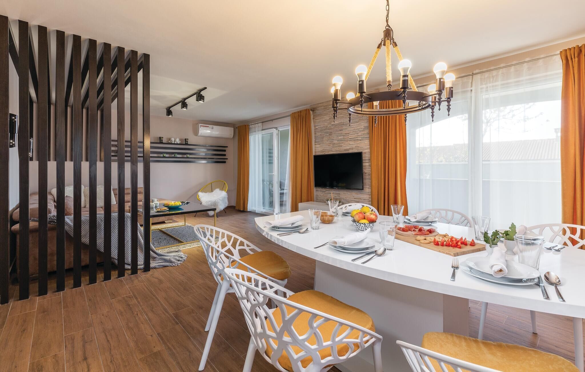 Une cuisine moderne dotée d’un îlot central, de chaises blanches et d’une table à manger dressée pour six personnes.
