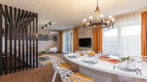 A modern kitchen with a central island, white chairs, and a dining table set for six. - Amazing home in Mihatovici (Mihatovici)