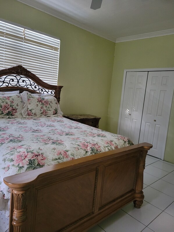 A bedroom with a wooden bed, a nightstand, a wardrobe, and a window with blinds.