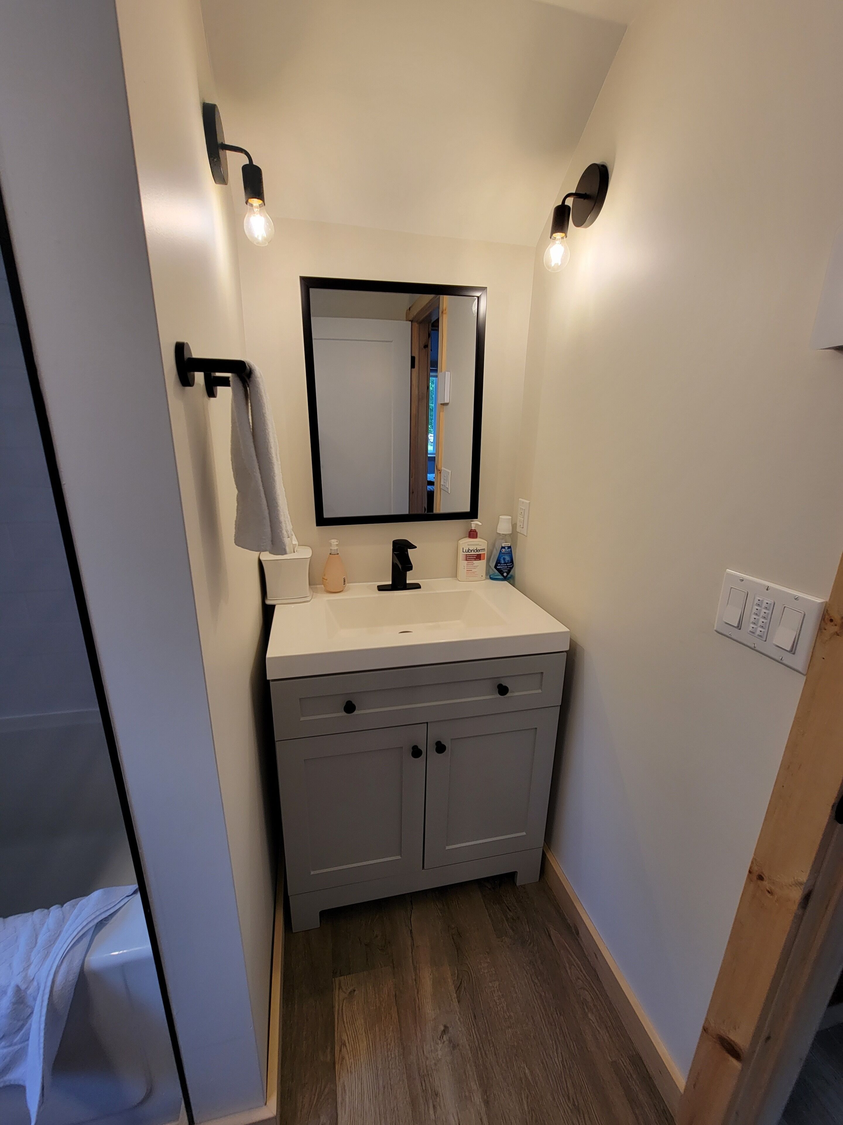 Un baño con un lavabo blanco, un espejo y dos luces empotradas.
