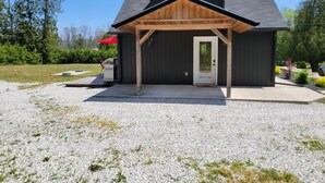 A modern house with a covered porch, a gravel driveway, and a red umbrella.