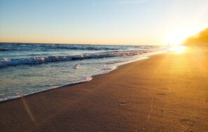 Une plage avec un coucher de soleil sur l’océan.
