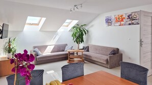 A modern living room with a sofa, a dining table with fruit, and a large plant. - Awesome apartment in Dobrzyca with WiFi (Dobrzyca)