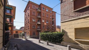 A narrow street with a red brick building featuring multiple balconies and windows. - Appartamento a Piazza dell'Unità by Wonderful Italy (Bologna)