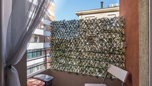 A balcony with a metal fence, a white chair, and a small table with a red and orange cover. - Appartamento a Piazza dell'Unità by Wonderful Italy (Bologna)