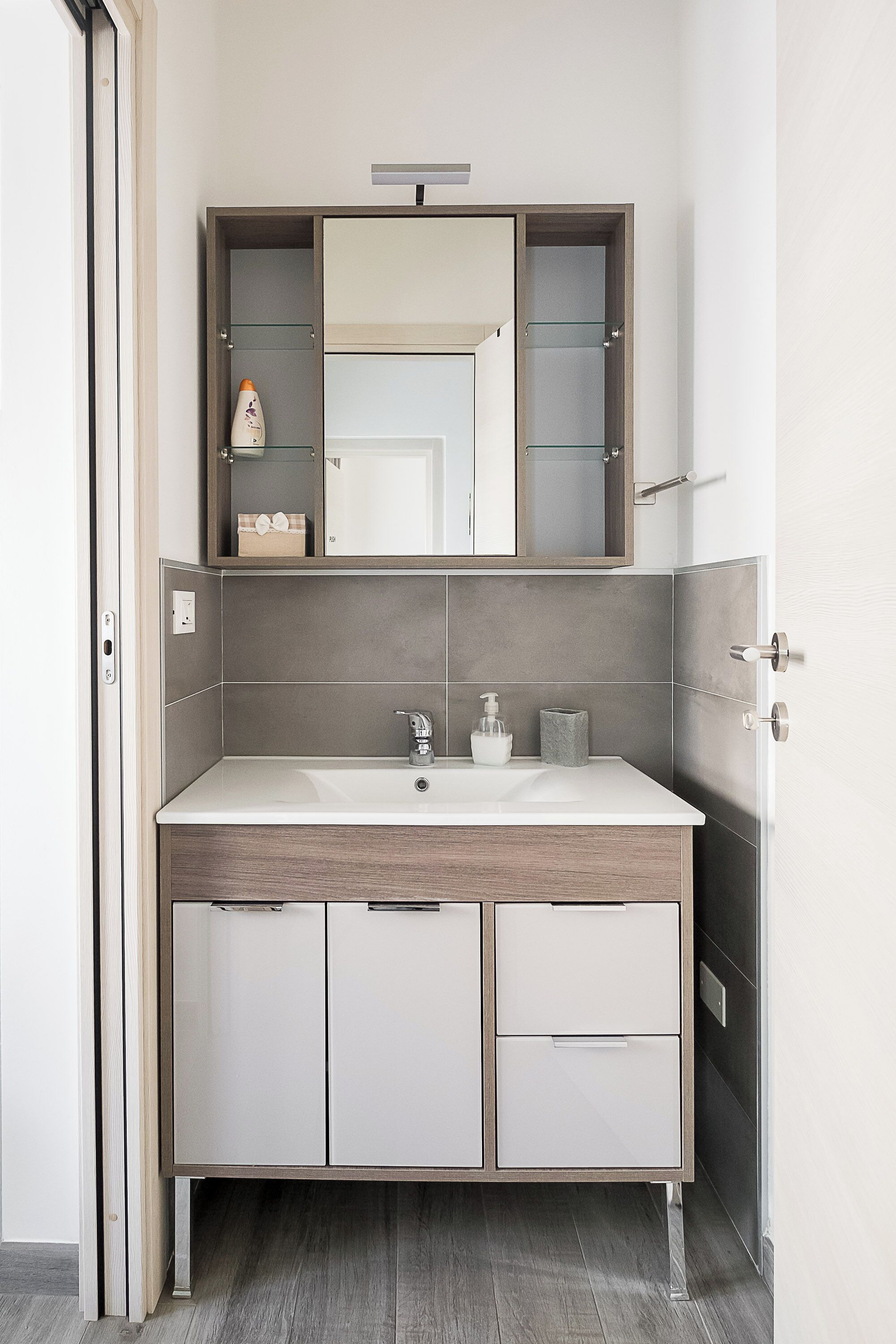 A modern bathroom with a large mirror, a sink, and cabinets.