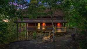 A log cabin with a stone foundation, wooden deck, and a staircase leading to the entrance. - Rustic Pigeon Forge Cabin - Mountain View/King Beds/Hot Tub/Minutes to Dollywood (Sevierville)