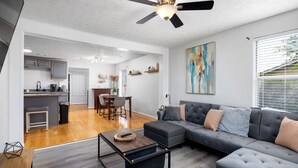A modern living room with a sectional sofa, a coffee table, and a dining area with a table and chairs. - 5 bedroom Family campus with three separate kitchens 15 min from Ft Moore (Columbus)