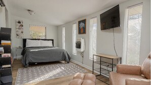A bedroom with a bed, a TV, a desk, and a chair. - 5 bedroom Family campus with three separate kitchens 15 min from Ft Moore (Columbus)